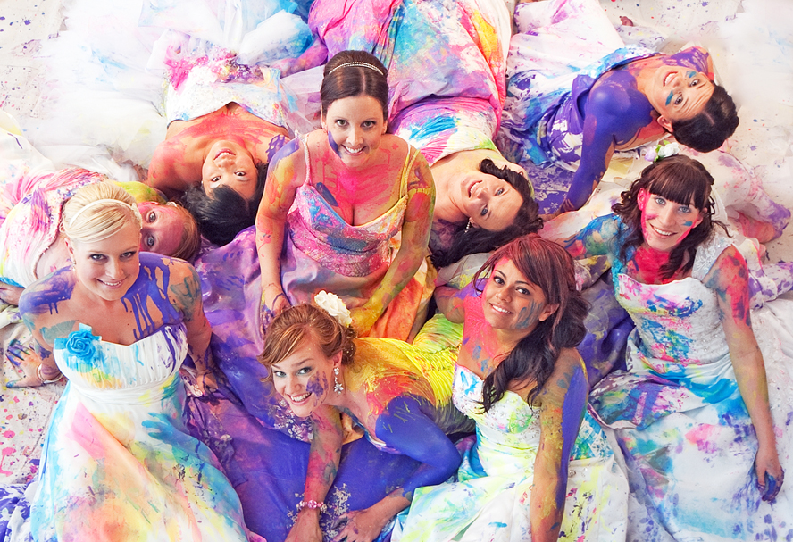 Bruiden geportretteerd van boven, hun trouwjurk vol verf bij een Trash the dress event