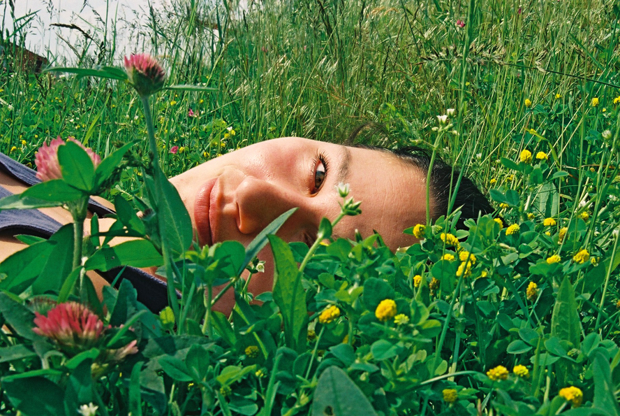 Portret Melanie E. Rijkers slow in flow, liggend in gras, analoog jaren '90